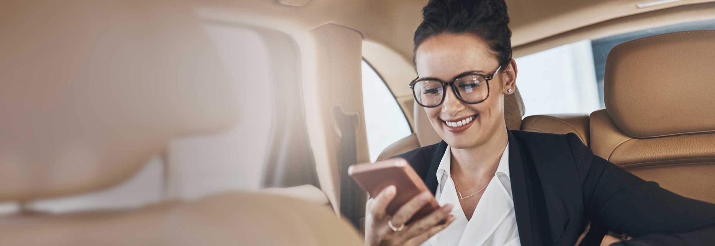 Commercial banker sitting in the back seat of the car using their phone